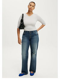 Woman wearing white long sleeve top and distressed blue jeans