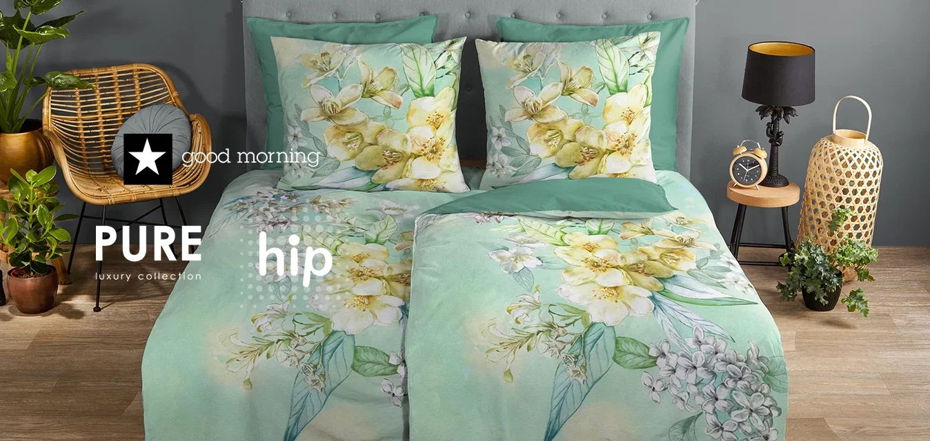 Blütenbettwäsche-Set in sanftem Mintgrün mit gelben und weißen Blumenmustern. Enthält zwei passende Kissen, inszeniert vor einer grauen Wand.