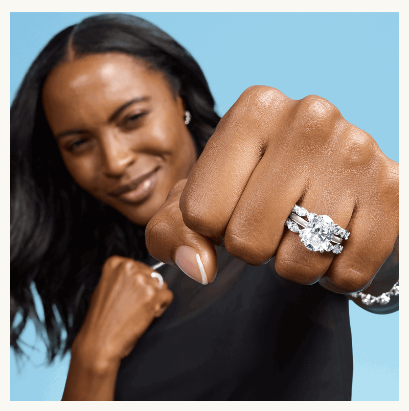 Model with thick, oval-cut diamond ring & eternity bands.