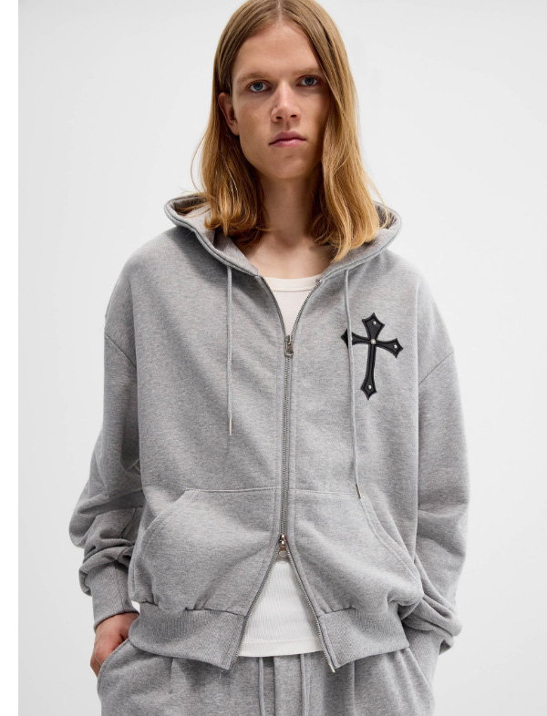 Man wearing a grey hoodie decorated with a cross