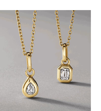 Two yellow gold necklaces featuring bezel-set pear-shaped and emerald-cut diamonds.