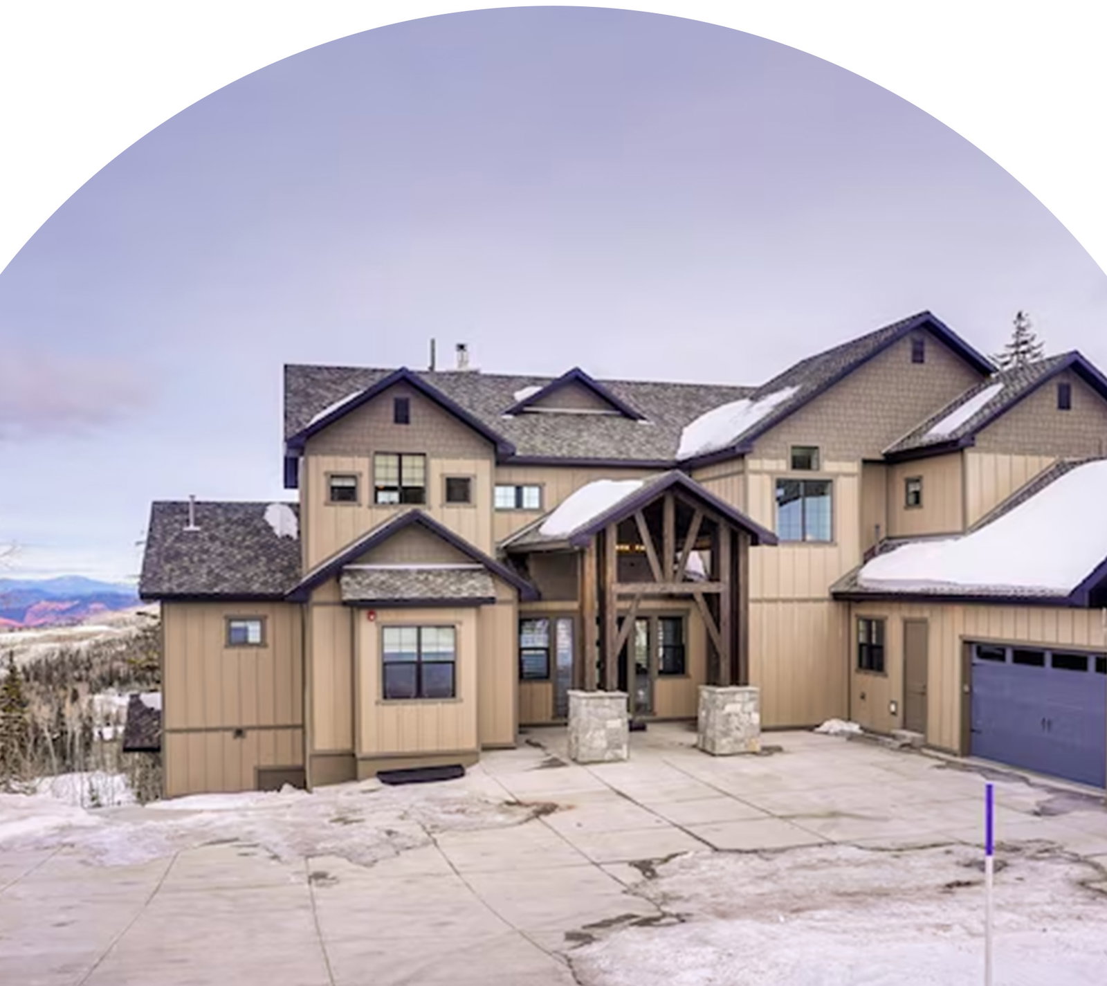 Snow-dusted mountain home with timber entry and attached garage.