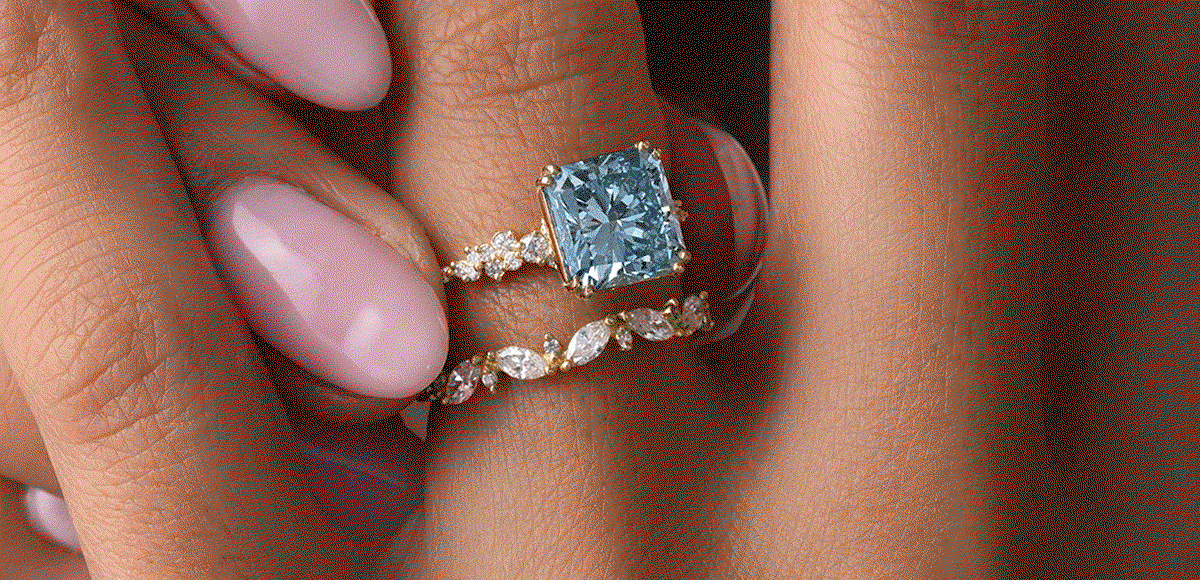 Several radiant cut engagement rings with colored center stones, shown being worn by models in a gif