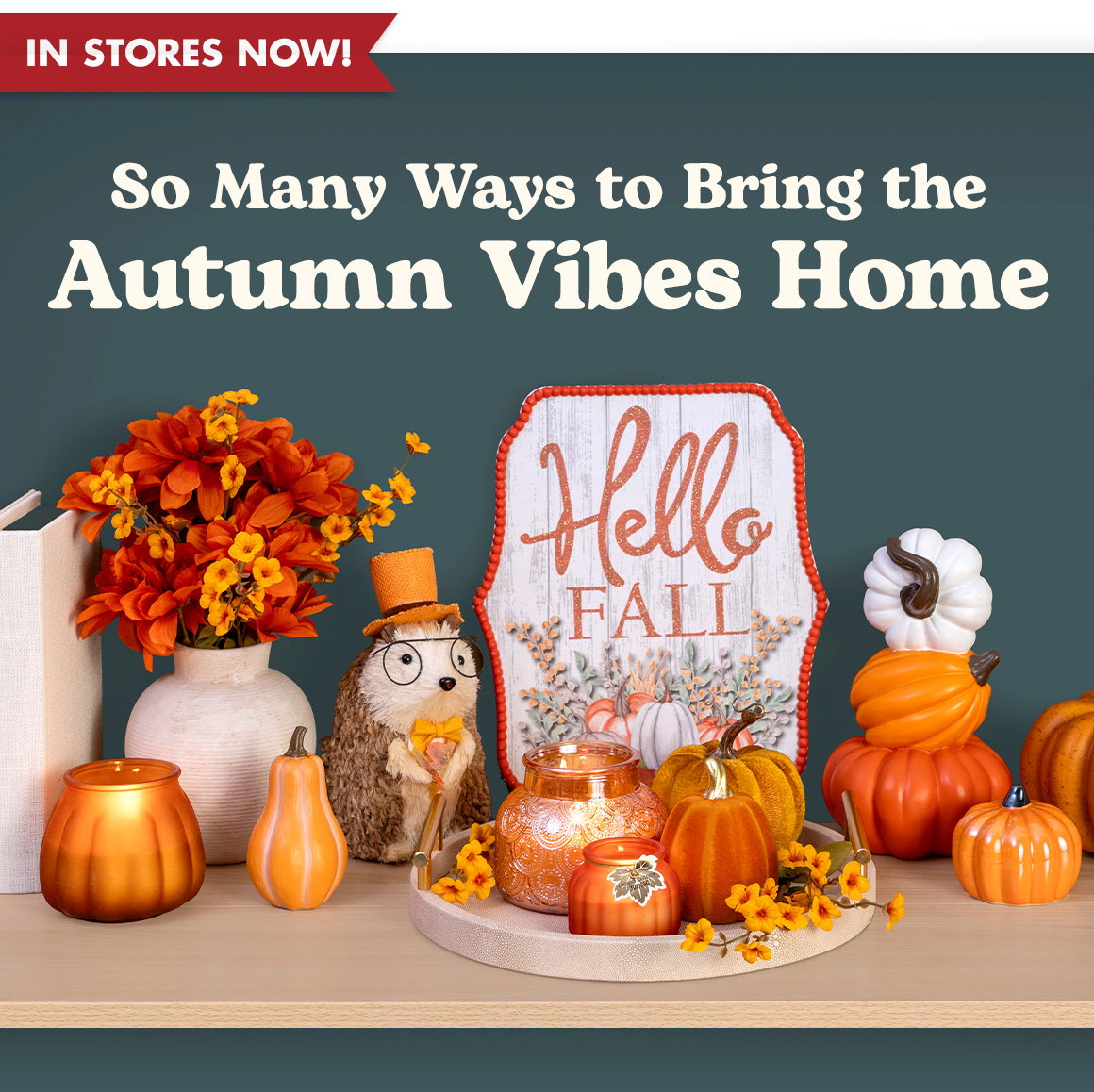 So Many Ways to Bring the Autumn Vibes Home. Image of fall-themed candles, pumpkin decorations, flowers, and a decorative sign on a table.
