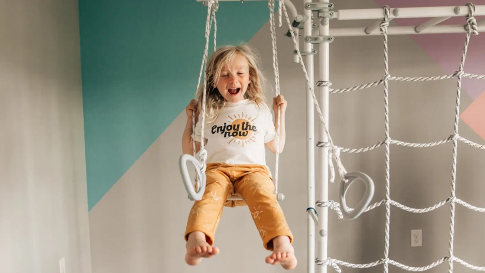 A child swinging on a Brainrich indoor gym at home