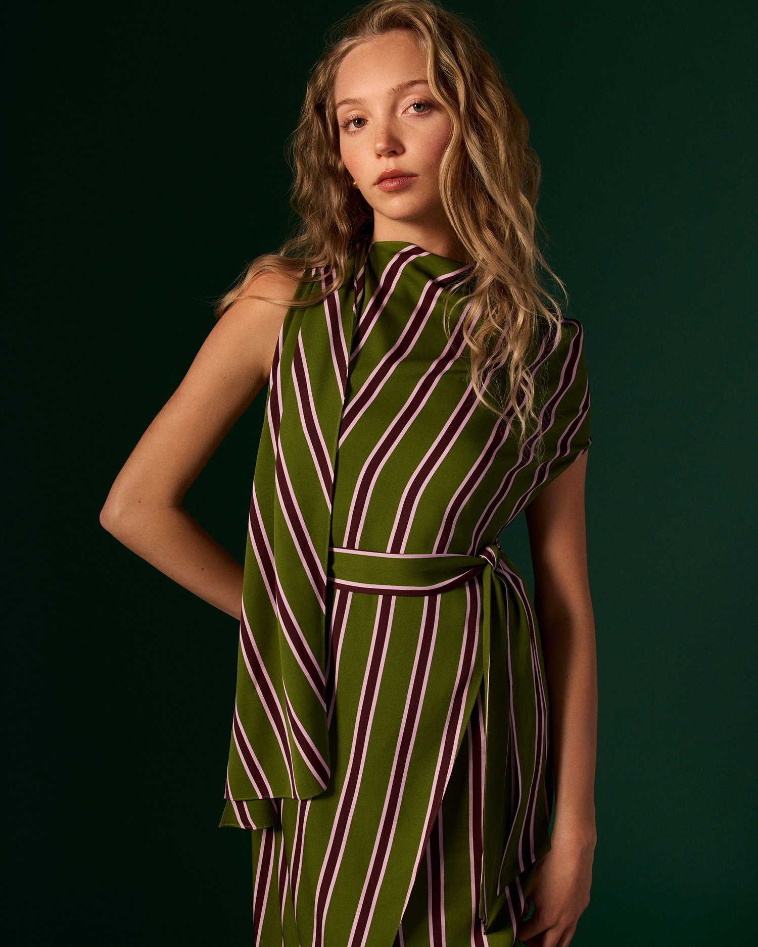 Model standing against green wall in the nora dress by DVF