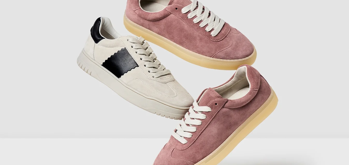 Drei Paar Sneaker ausgestellt: ein pinkes Wildlederpaar, ein cremefarbenes Wildlederpaar mit einem schwarzen Akzent und eine sandfarbene Gummisohle.