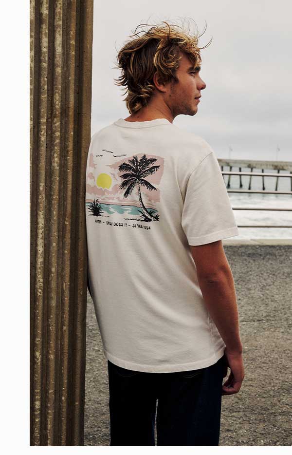 Male model standing at the beach wearing the Bien Tee.