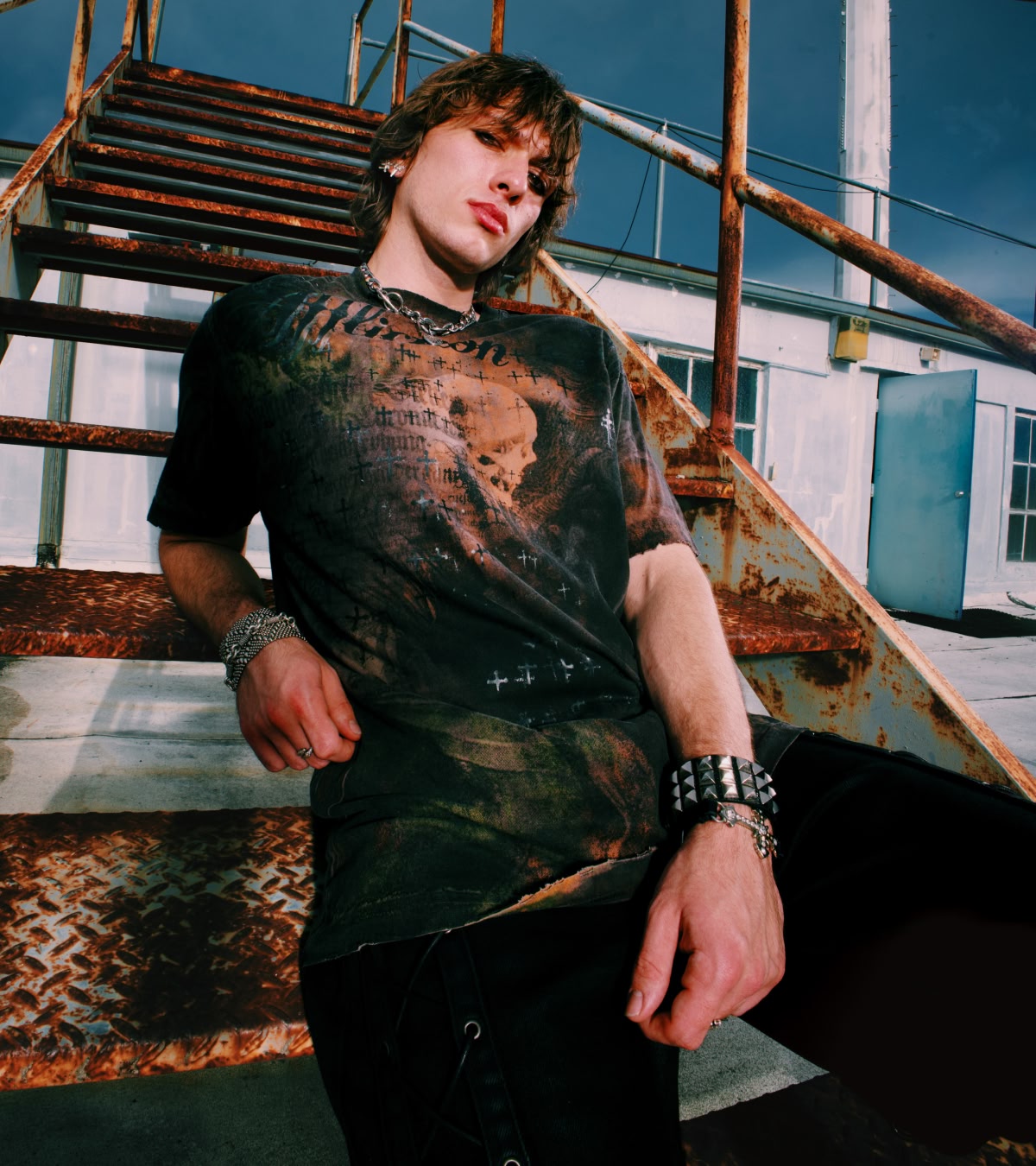 Shop Affliction x Rogue | An emo boy wearing one of the tees while leaning on school bleachers