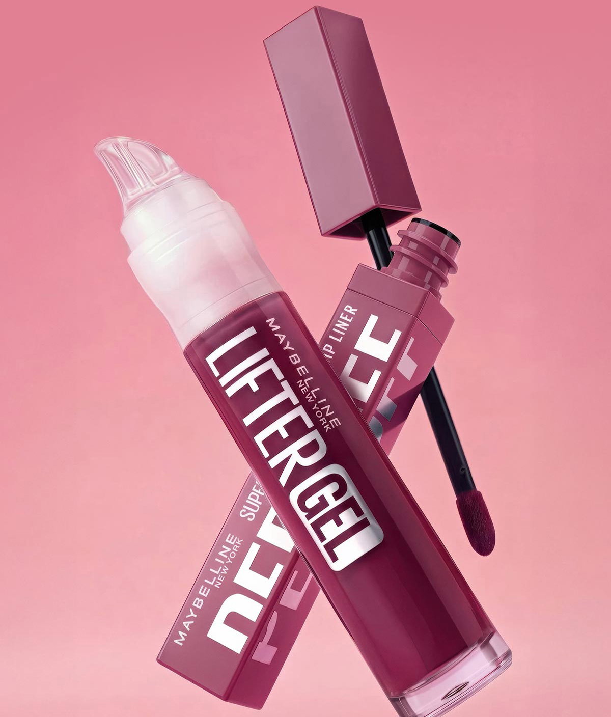 Lifestyle image of Maybelline Super Stay Peel-Off Lip Liner and Lifter Gel Lip Gloss in coordinating berry-pink shades, shown floating against a soft pink background.
