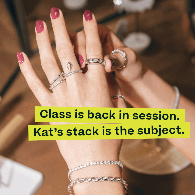 Hand with silver-set & diamond accented ring stack. Class is back & Kat’s stack is the subject.