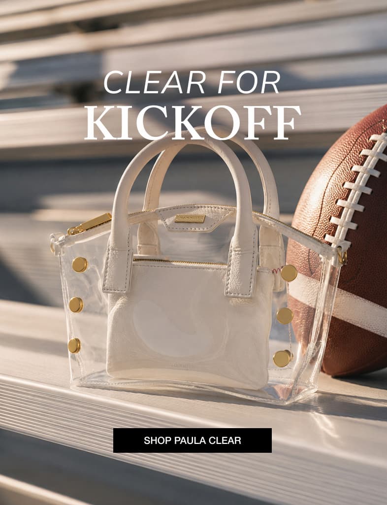 Clear Paula bag with white leather accents and gold rivets styled beside a football on stadium bleachers.  Image Copy: CLEAR FOR KICKOFF  CTA Copy: SHOP PAULA CLEAR