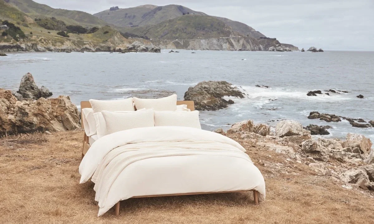 A Coyuchi organic bed styled on a Big Sur cliff overlooking the ocean