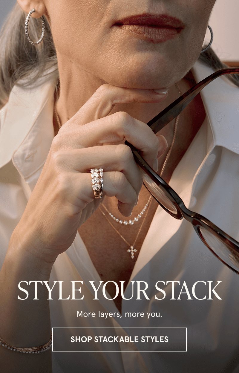 A model wearing gold diamond jewelry holds a pair of glasses. Style your stack. Click here to shop stackable styles