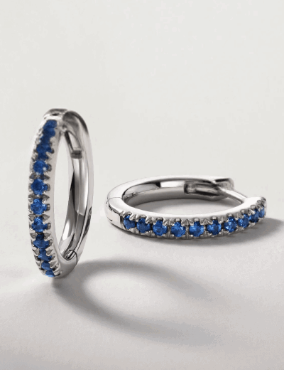 Blue sapphire hoop earrings in a silver-tone setting.