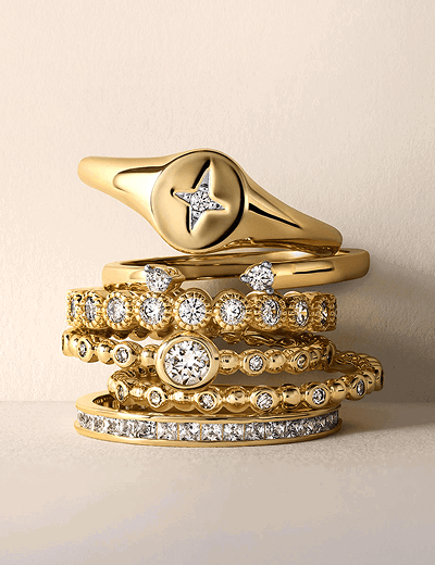Stacked yellow gold rings and bands with diamond accents.