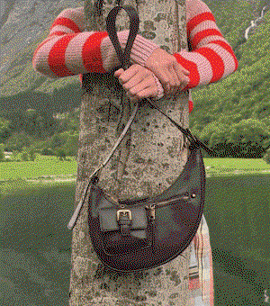 GIF of a model standing next to a lake holding a leather bag