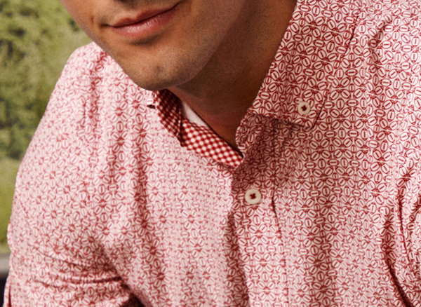 Close-up of a model wearing a red team-inspired patterned button-down shirt.
