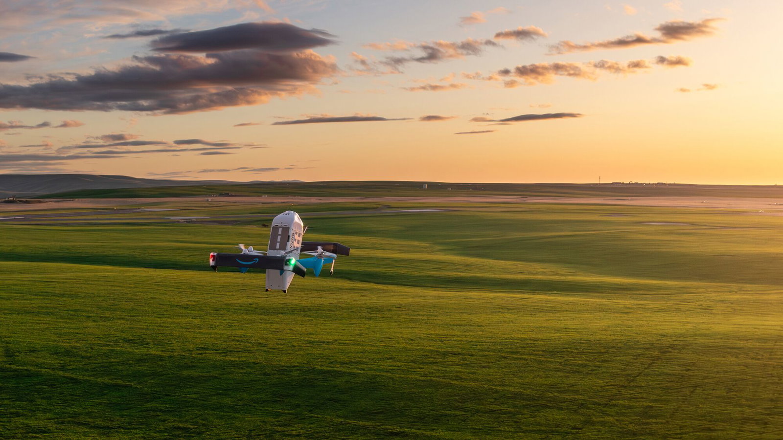 Prime Air delivery drone flying above a field at sunset. 