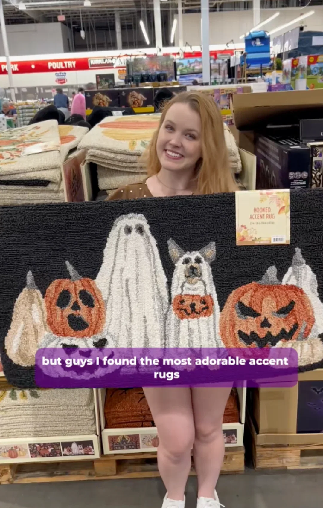 girl smiles holding halloween door mat inside Costco