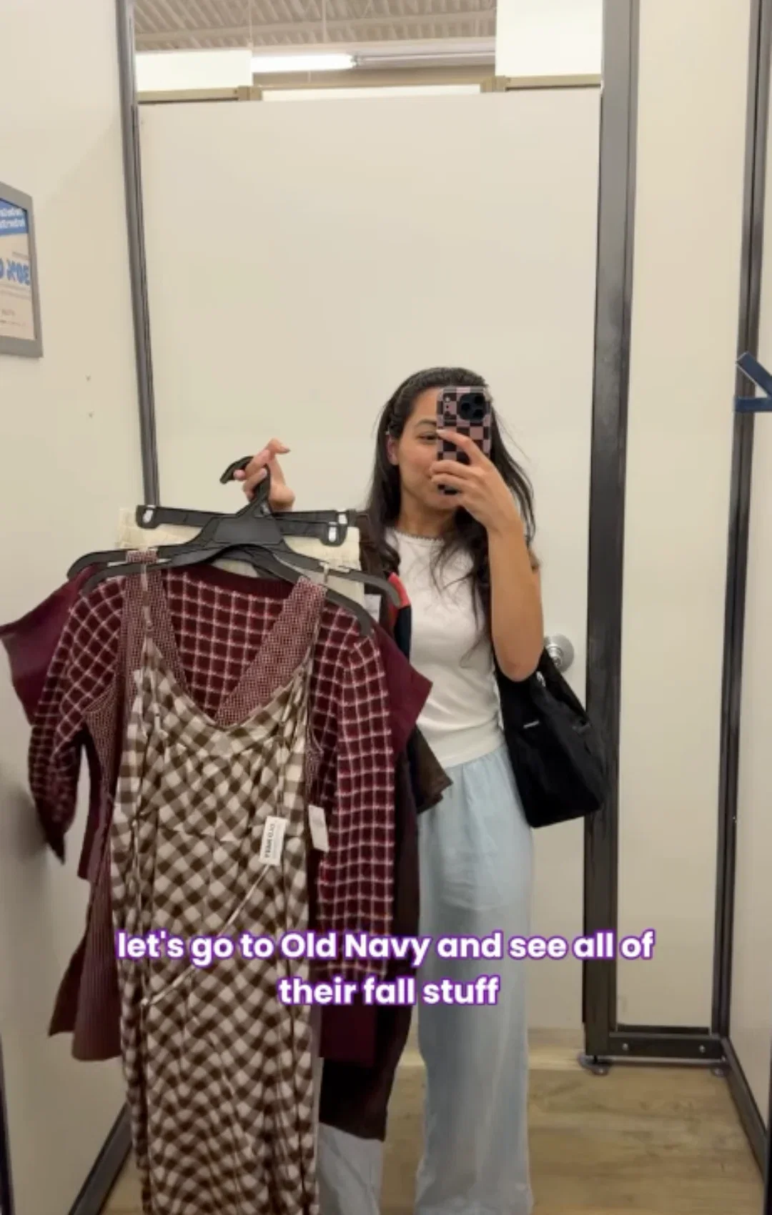 Olivia takes selfie while holding clothes in Old Navy dressing room