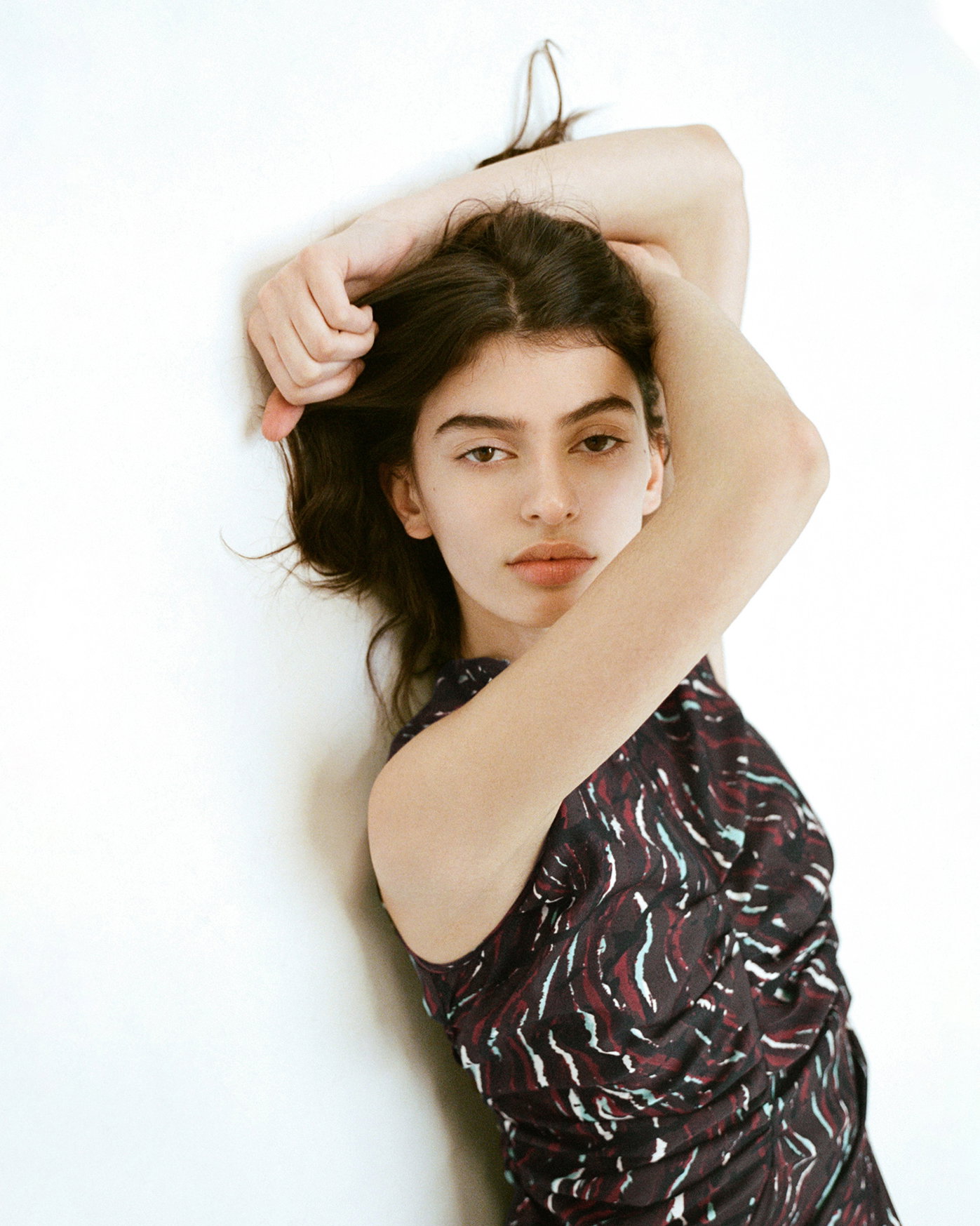 Cropped Image of model laying on a blank surface wearing the Clem Dress in Printed Soft Twill in Coffee Multi