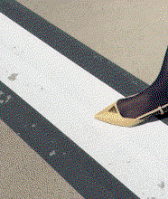 Cream pointed slingback shoe stepping across white road markings.