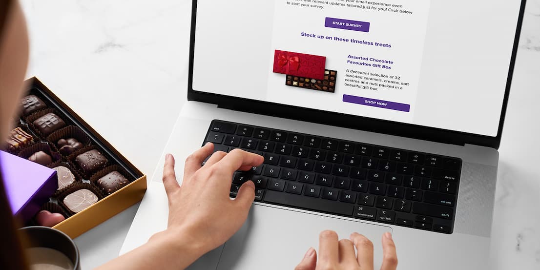 A laptop next to a box of chocolates
