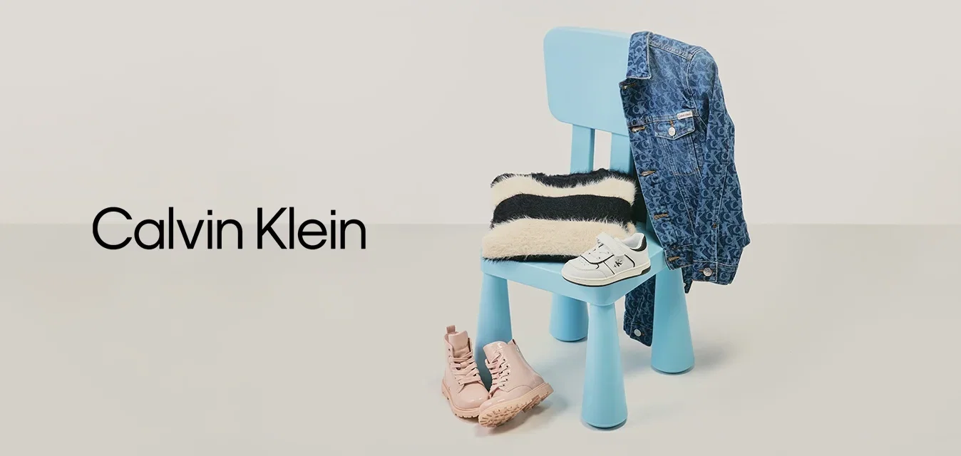 Blauer Stuhl mit gestreiftem schwarz-weißen Pullover, Jeansjacke hängt am Rücken, weiße Kleinkinderschuhe auf der Sitzfläche und rosa Stiefel auf dem Boden.