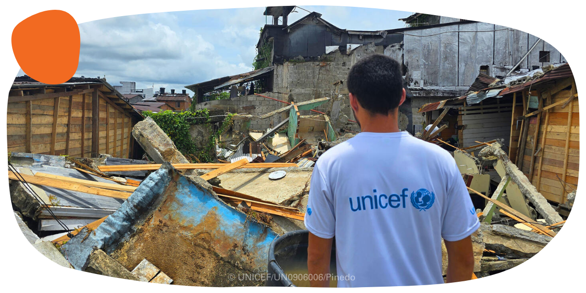 A UNICEF worker standing in front of rubble