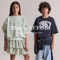 Zwei Kinder stehen nach vorne gerichtet; das Mädchen trägt ein blassgrünes Sweatshirt und einen Rock, der Junge trägt ein dunkles T-Shirt mit 