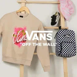 Beiger Vans-Sweatshirt, schwarz-weiß karierten Rucksack, rosa gemusterter Fischerhut und schwarze Babysneaker auf einer Holzleiter präsentiert.