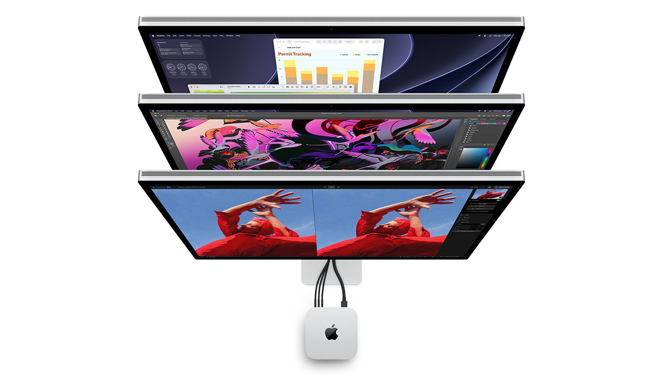 Three stacked displays are arranged vertically, each showing different creative workspaces, with cables running to a silver Mac mini centered beneath them.
