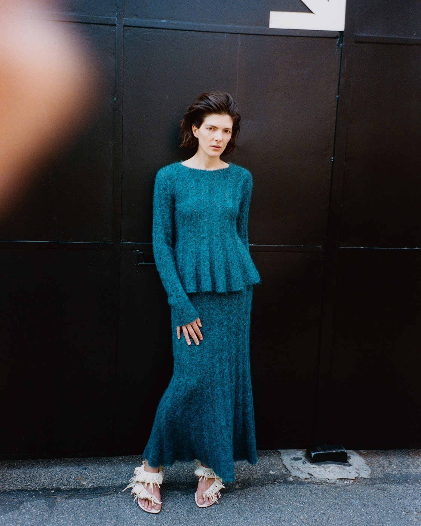 Campaign image of model wearing the Joelle Top in Looped Mohair in Blue multi and the Joelle Skirt in Looped Mohair in Blue Multi with the Tee 85 Loop Sandal in Nappa in Ecru