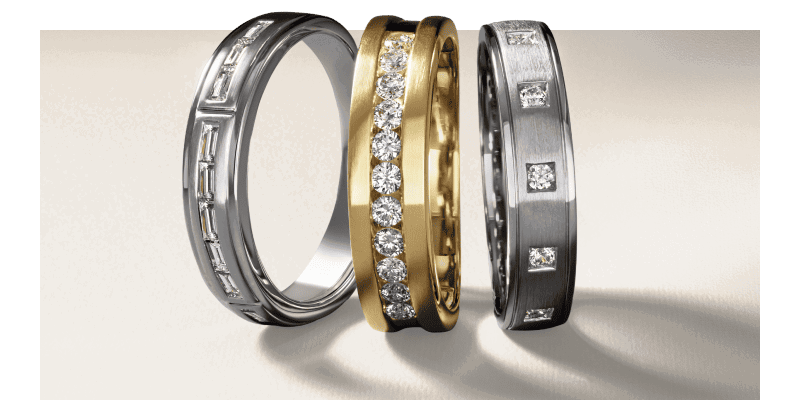 Three white and yellow gold wedding bands with round and baguette diamonds.