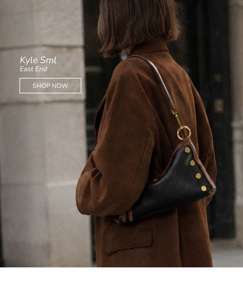 Kyle Sml — East End Alt Text: Model wearing the Kyle Sml shoulder bag in black and brown leather with gold rivets over a brown jacket.