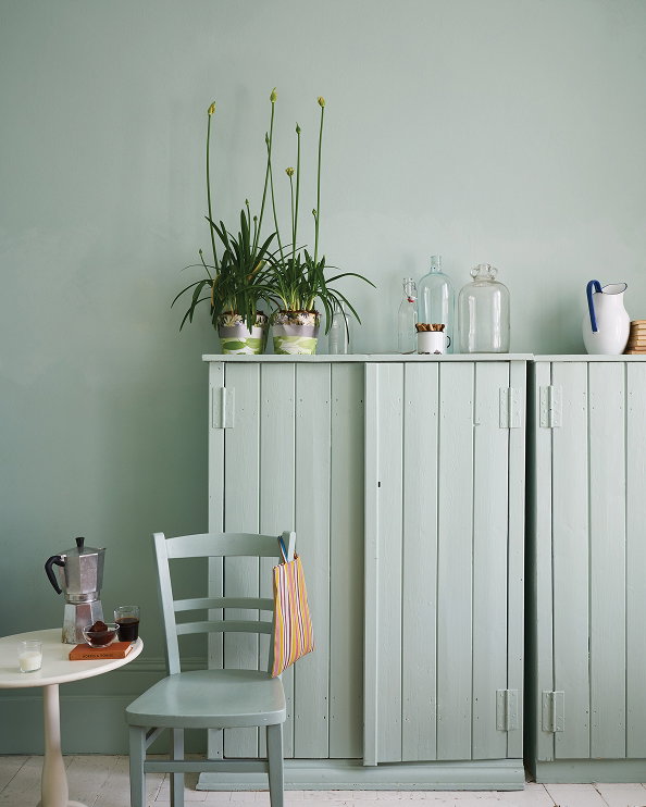 Soft green dining space featuring walls, a painted wooden cupboard, and a matching chair in Teresa's Green No.236, styled with potted plants, glass bottles, and ceramic accessories.