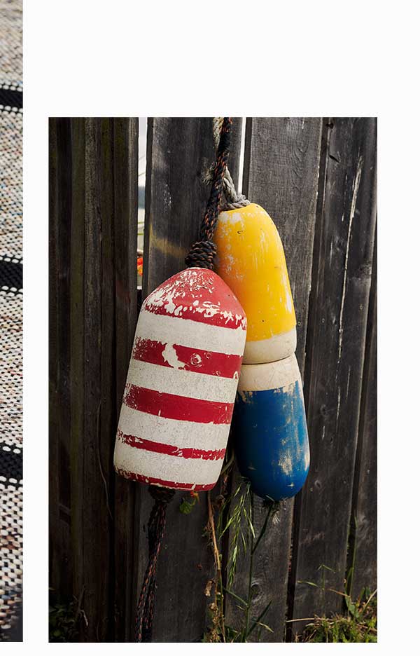Colorful boat buoys hanging on timber fence.