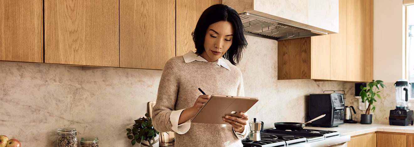 Woman using a tablet in a modern kitchen.