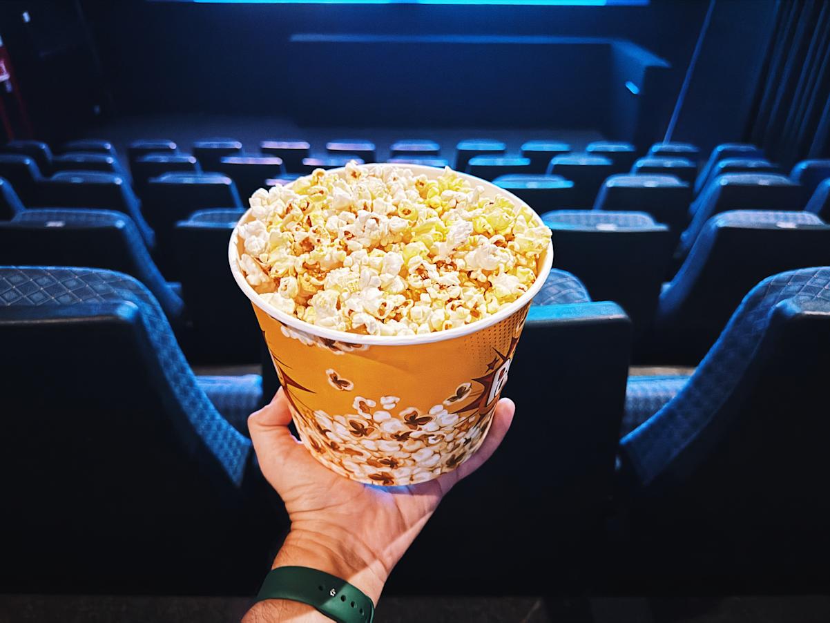 Stock photo of a person holding popcorn at a movie theater