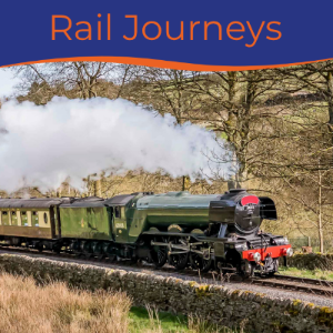 A steam train travels along a scenic railway surrounded by trees and greenery.