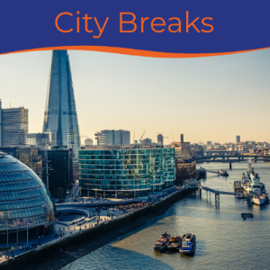 A panoramic view of a city skyline with modern buildings along a river, featuring boats on the water.
