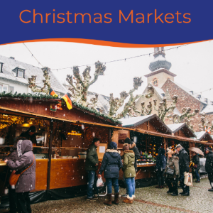 Snowy Christmas market scene with wooden stalls and people browsing festive goods.