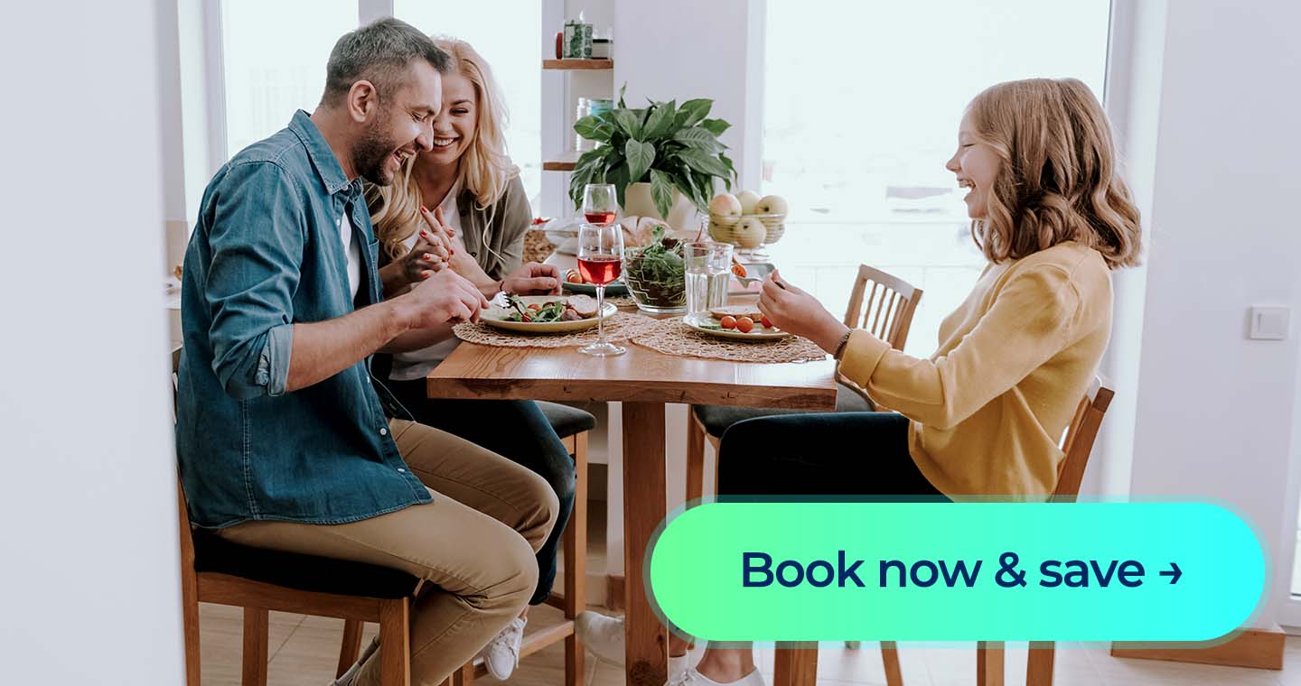 A mother, father and daughter eating dinner while laughing