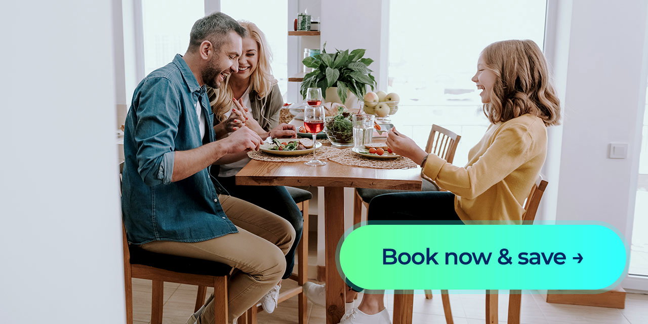 A mother, father and daughter eating dinner while laughing