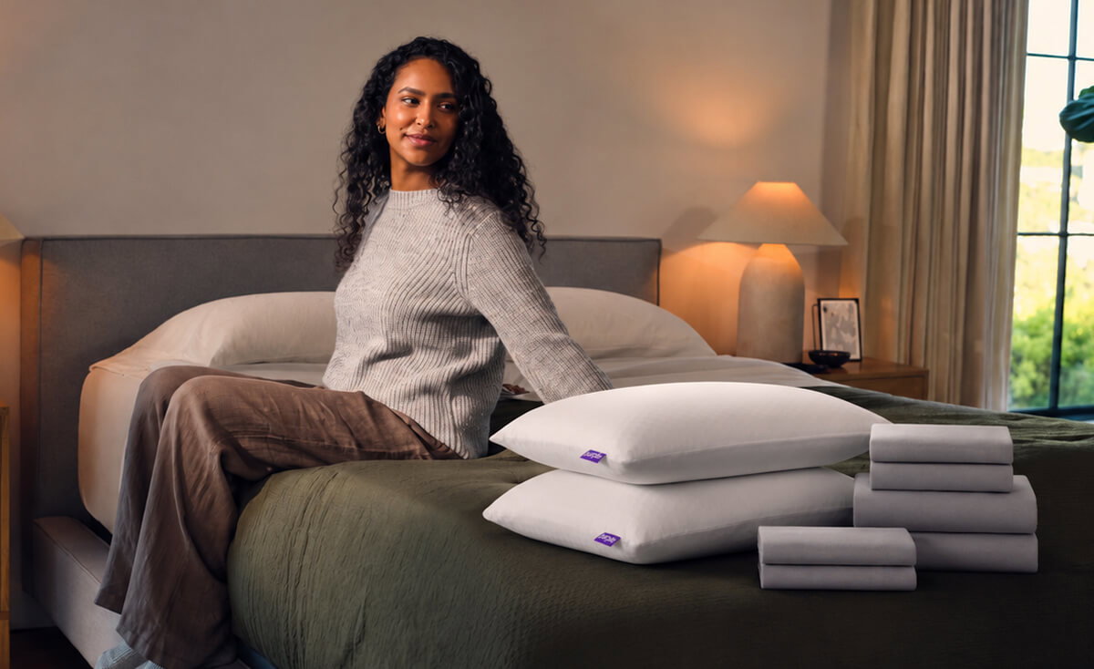 Woman sitting besides pillows on a bed