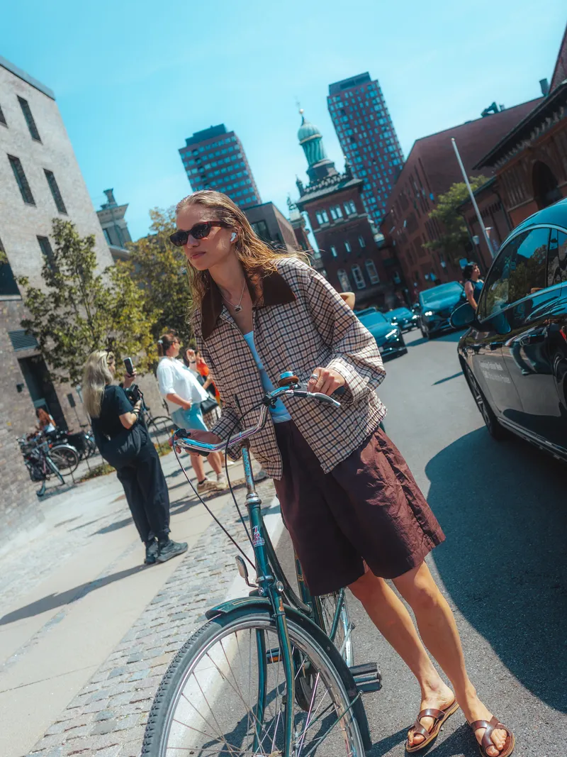 Image may contain: Kate Beaton, City, Road, Street, Urban, Adult, Person, Teen, Machine, Wheel, Clothing, Shorts, and Car