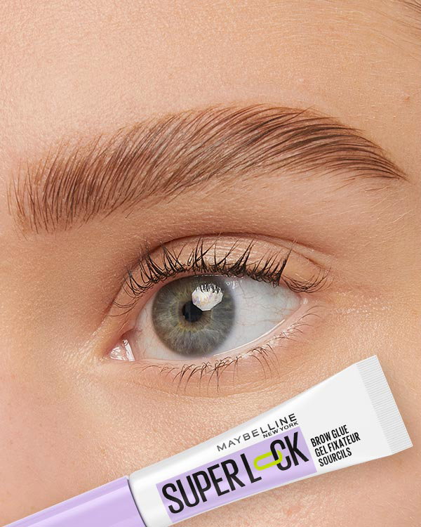 Close-up of a laminated blonde eyebrow above a blue eye, with a Maybelline Super Lock Brow Glue shown below to support a sculpted brow routine.