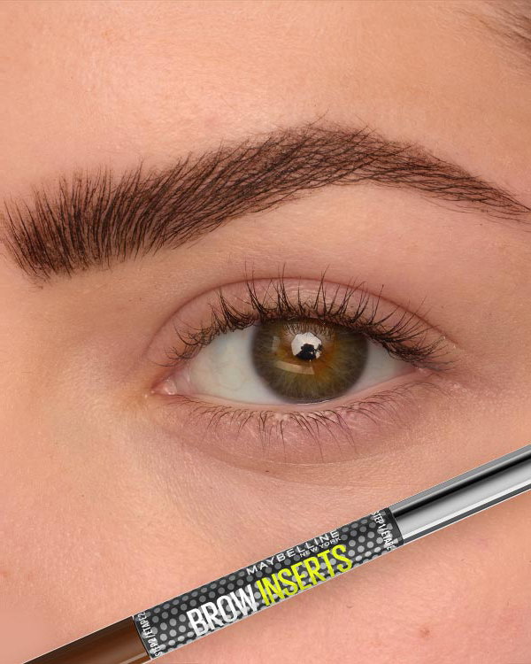 Close-up of a precisely filled brown eyebrow above a hazel eye, with a Maybelline Brow Inserts Multiplying Tool pencil shown below to support a salon-quality brow routine.
