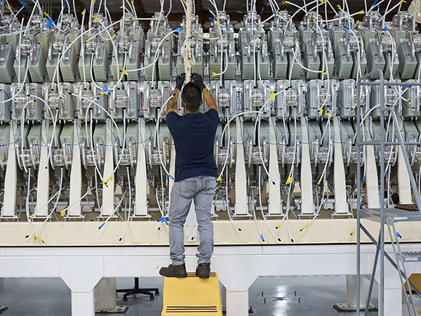 A technician wearing gloves stands on a stool, assembling part of a truck-sized module that is part of Pacific Fusion’s machine.
